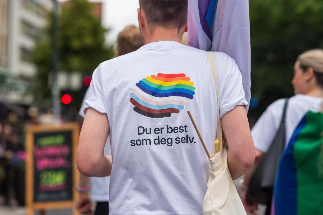 En person med kort hår og en hvit t-skjorte hvor det står "Du er best som deg selv".